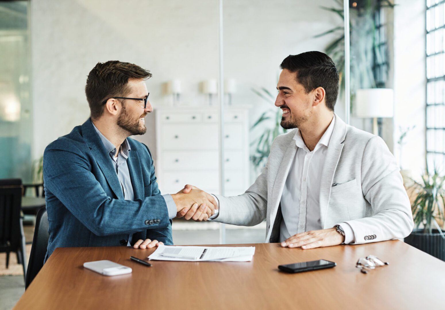 Two men shaking hands at desk